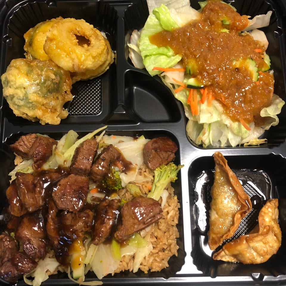 Fugu One bento box with beef teriyaki, fried rice, tempura, salad, and dumplings.