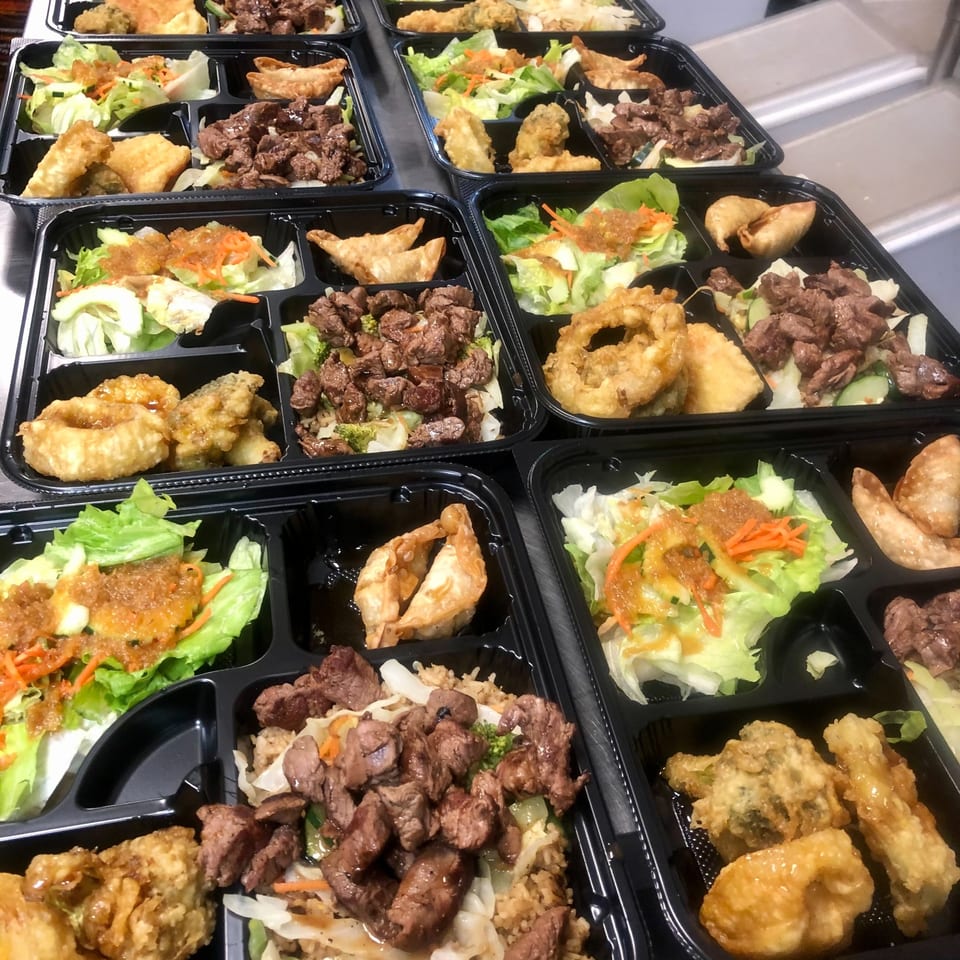 Multiple Fugu One Asian-fusion bento boxes with beef, salad, fried items, and dumplings.