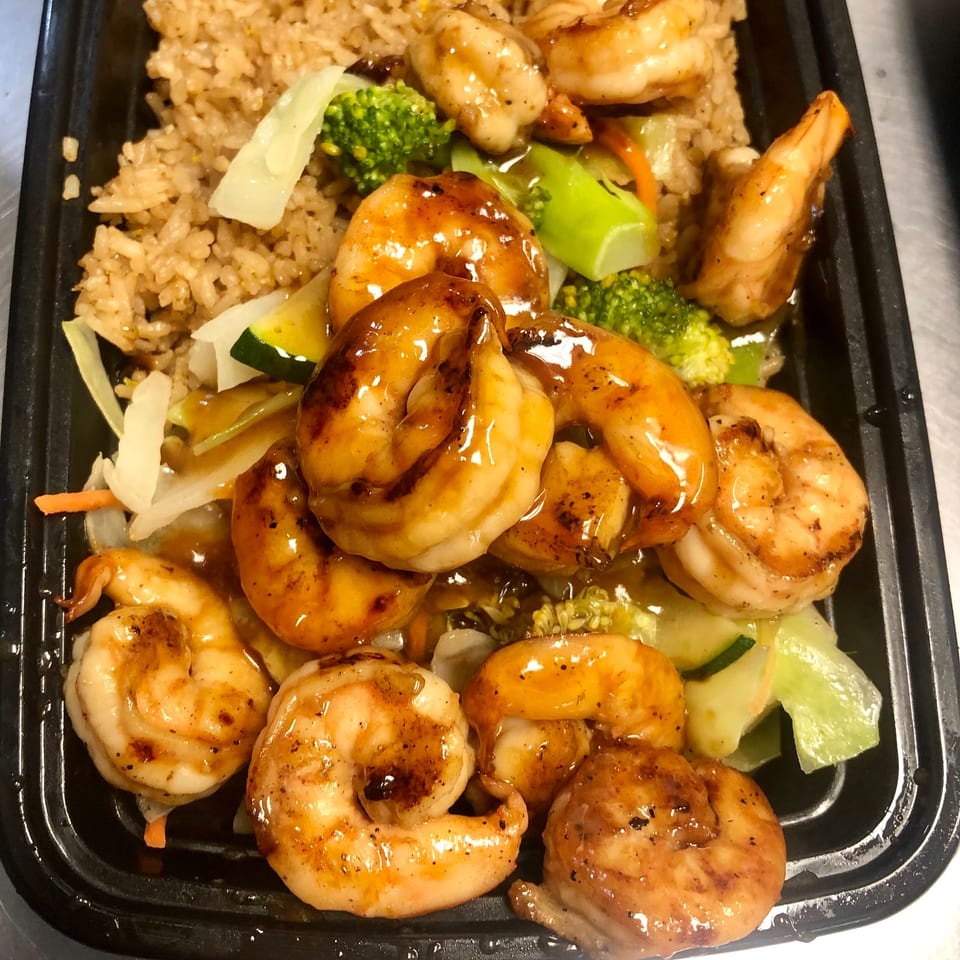 Fugu One's shrimp hibachi with fried rice, broccoli, zucchini, and carrots in a black takeout container.