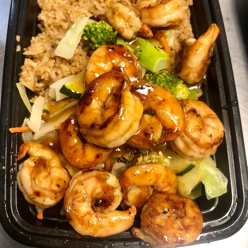 Fugu One's shrimp hibachi with fried rice, broccoli, zucchini, and carrots in a black takeout container.